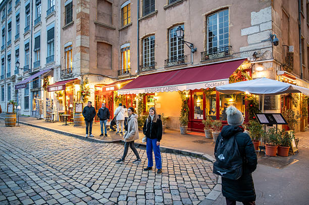 Lyon, france. December 29, 2023. People exploring the historic vieux lyon district in france, enjoying the illuminated brasserie gabriel and charming atmosphere at dusk