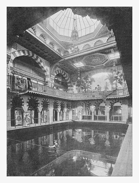 A black and white illustration from the 19th century depicting a luxurious indoor ladies' swimming bath. The architecture is in the opulent Moorish Revival style, featuring striped horseshoe arches, intricate tilework, and ornate balconies. In the center, a woman performs on a tightrope stretched across the pool, while other women in period swimwear watch from the side and the upper gallery. The scene is illuminated by a large glass skylight.