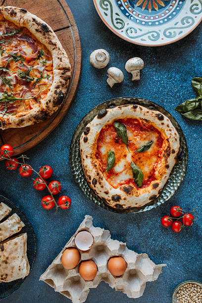 Delicious Neapolitan pizzas with fresh ingredients and rustic presentation on a blue table