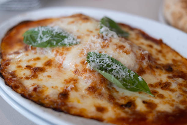 Classic margherita pizza with melted mozzarella cheese, fresh basil leaves and rich tomato sauce, close up Italian comfort food on white plate, traditional restaurant style cuisine.