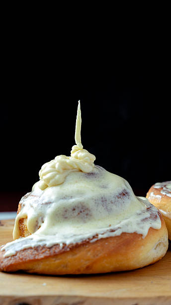 Cinnamon roll with cream cheese frosting on wood