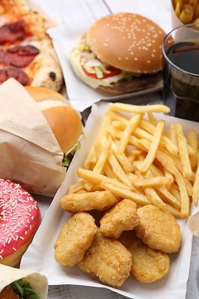 Different delicious fast food on light wooden table, closeup