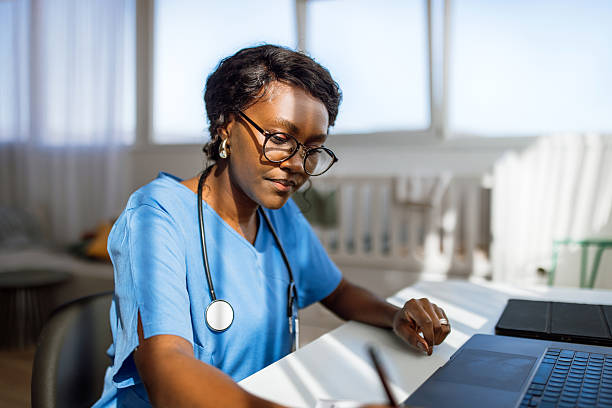 Female Doctor In Office Working At Laptop And Doing Paperwork