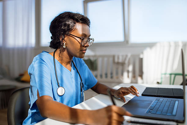 Female Doctor In Office Working At Laptop And Doing Paperwork
