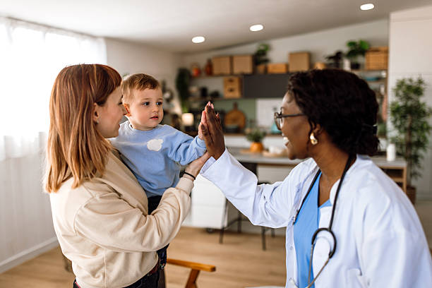 Female pediatrician at home visit, leaving after health examination. Doctor and boy giving a high five gesture.