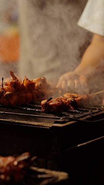 Close-up of hands grilling chicken skewers on a charcoal grill