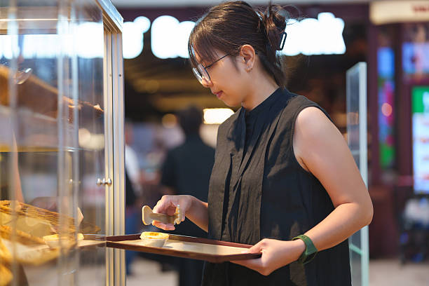 Asian Woman Selecting Pastries in Bakery Shop