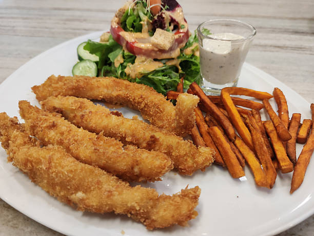 Crispy Breaded Chicken Strips Served with Fresh Garden Salad, Sweet Potato Fries, and Creamy Dipping Sauce on a Modern White Plate
