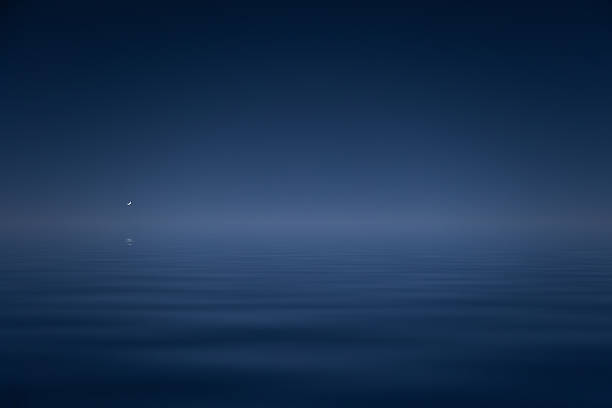 Bright moon above calm blue sea surface with clean negative space and simple minimalist background, creating serene tranquil peaceful natural ocean scenery at night