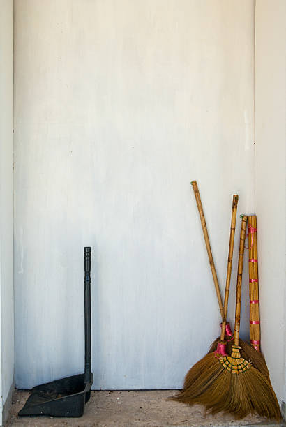 Cleaning tools including a dustpan and brooms standing in a corner