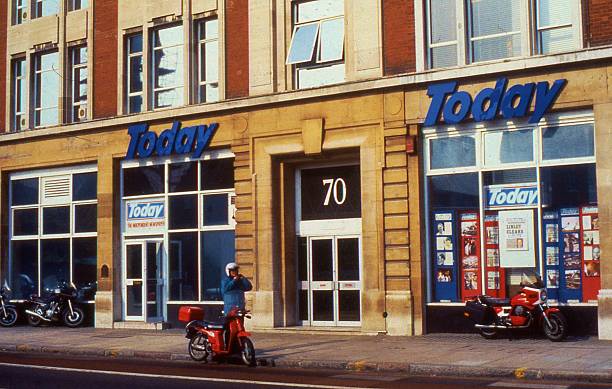 London, England - March 30, 1990: Archive film image of a motorcycle rider stands outside the headquarters of British national newspaper Today. Launched in March 1986, the daily paper ceased publication in 1995.