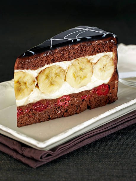 Chocolate cake slice with banana strawberry cream filling and web glaze on dessert plate