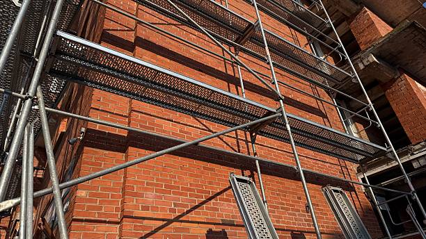 Steel Scaffolding Structure on Historic Red Brick Building Facade Against Clear Blue Sky — Urban Renovation and Heritage Architecture Restoration Concept, Perspective Construction Shot