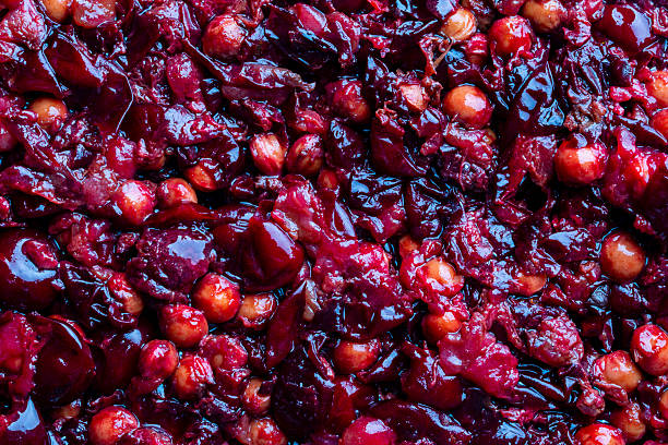 Red cherry pits and pulp after squeezing out the juice as a background, closeup. Texture of cherry kernels. Top view