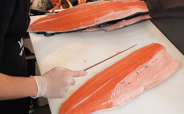 Chef Filleting Fresh Salmon on a Cutting Board