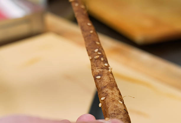 Crunchy Salty Pretzel Rod with Sesame Seeds, Close-up in Hand