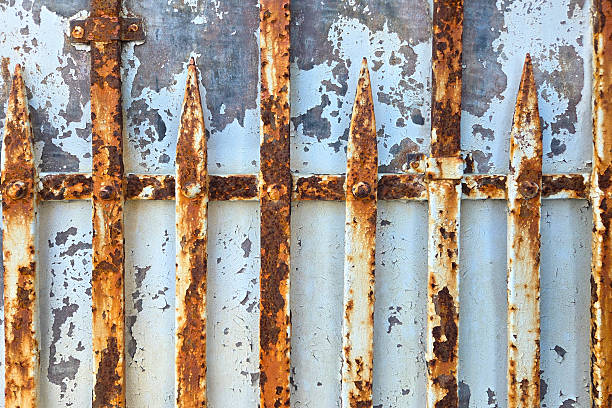 Weathered metal gate featuring rusted vertical bars and peeling paint. ideal for industrial-themed designs or backgrounds, textures, decay, and urban aesthetics.