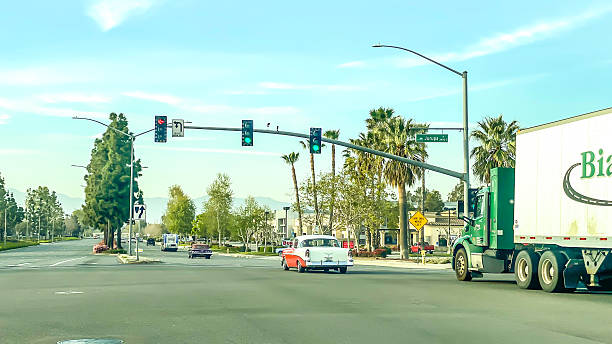 A vintage-style car drives through a street in La Jolla, California, contrasting with modern vehicles and surroundings. The image captures a sense of nostalgia and timeless design within a contemporary coastal city setting.