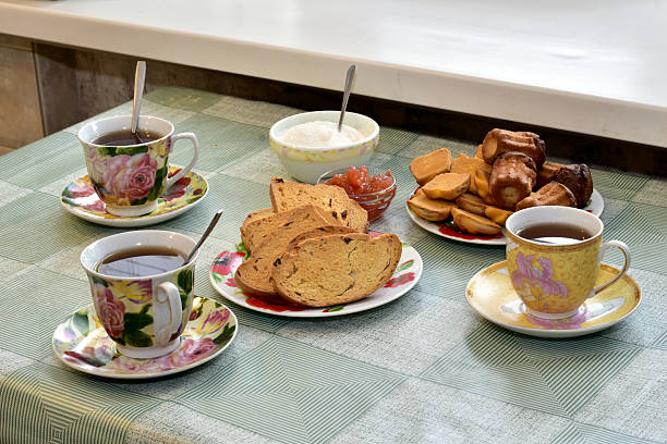 Several cups of tea, a vase of sugar and sweet crackers stand on the table.