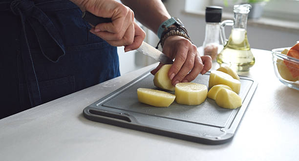 Woman Cutting Raw Potatoes