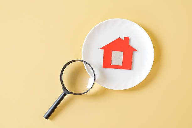 Minimal red house on white dish with magnifying glass .