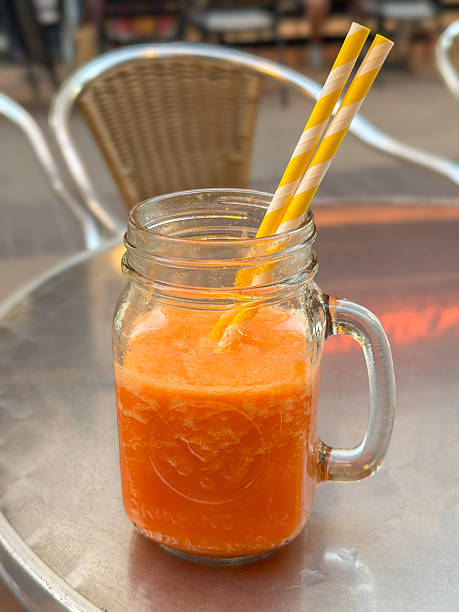 Fresh orange juice in mason jar with paper straws