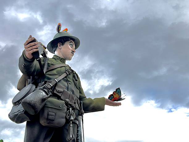 Valencia, Comunidad Valenciana, Spain - March 14, 2026: Fallas de Valencia sculpture depicting a soldier resembling Charlie Chaplin engaging with a colorful butterfly, representing themes of peace, art, and traditional spring renewal in Spain