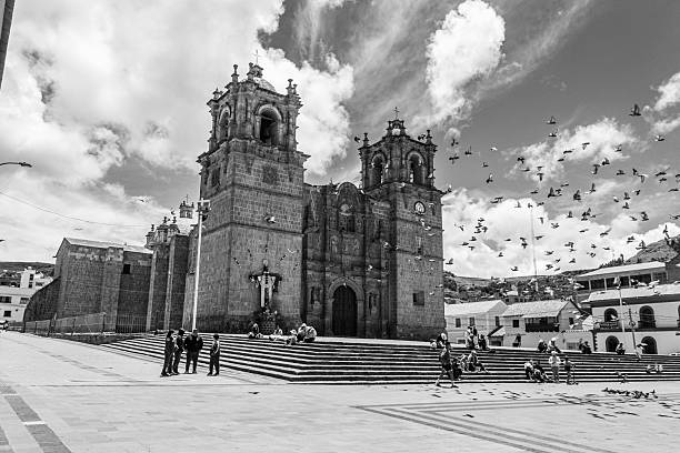 Puno District, Puno Region, Peru - February 18, 2026: Pigeons flying and Cathedral at Puno Main Square in black and white