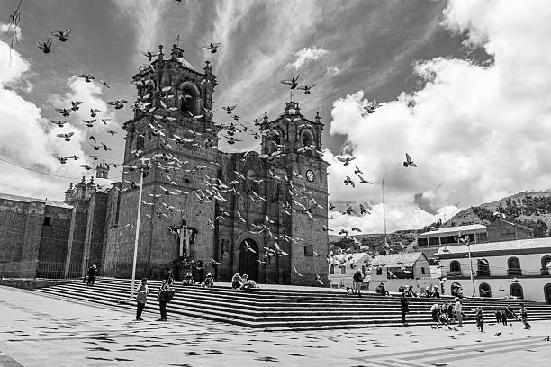 Puno District, Puno Region, Peru - February 18, 2026: Pigeons flying and Cathedral at Puno Main Square in black and white