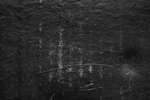 Black scratched grunge texture background, distressed paper surface with white dust and grain
