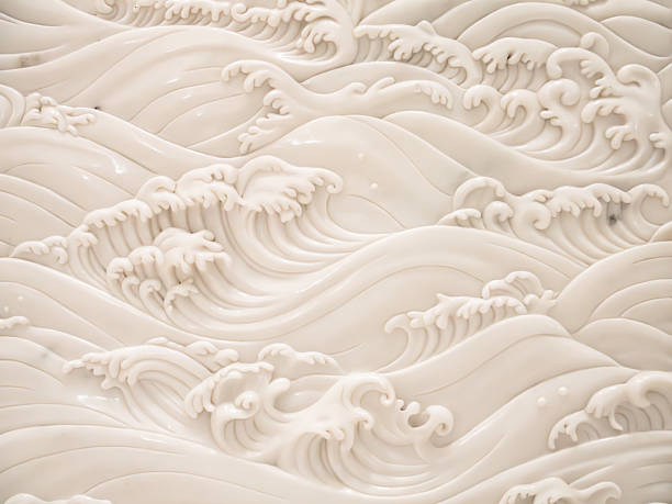 This image showcases a detailed relief sculpture crafted from polished white marble or high-quality stone, depicting a series of dynamic, cresting ocean waves. The artistic style is heavily reminiscent of traditional Asian wave motifs, featuring elegant, sweeping curves and intricate, frothy foam at the peaks of each swell. The monochromatic off-white palette emphasizes the play of light and shadow, highlighting the depth and tactile quality of the carving. The composition is rhythmic and fluid, creating a sense of continuous motion and serene natural power across the entire surface.