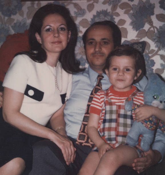 Image taken in the 1970s: Mid adult couple posing with their son looking at the camera