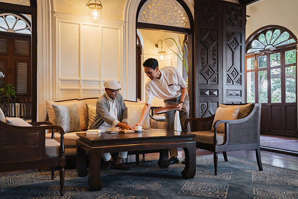 Waiter serving coffee to a mature man relaxing in an elegant hotel lounge.