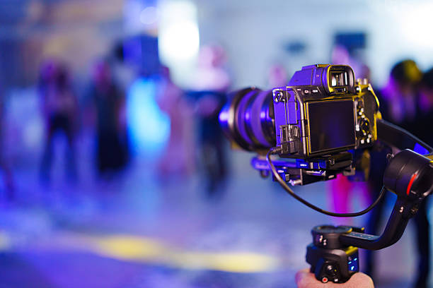 Camera on a stabilizer captures people at an event in the evening