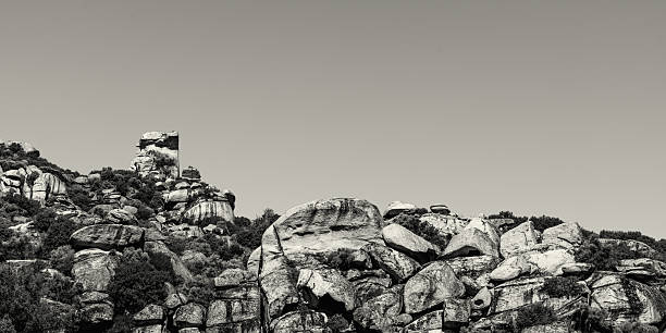 Dramatic sandstone boulder formations rise above Mediterranean scrubland in Gökbel Valley, Yatağan, Muğla, Turkey. Rendered in black and white, the monochrome treatment emphasizes the ancient textures and shapes of this geological geopark known as the 