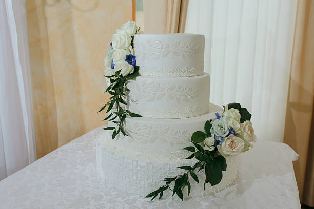 A white three tier wedding cake with blue flowers and white flowers on it