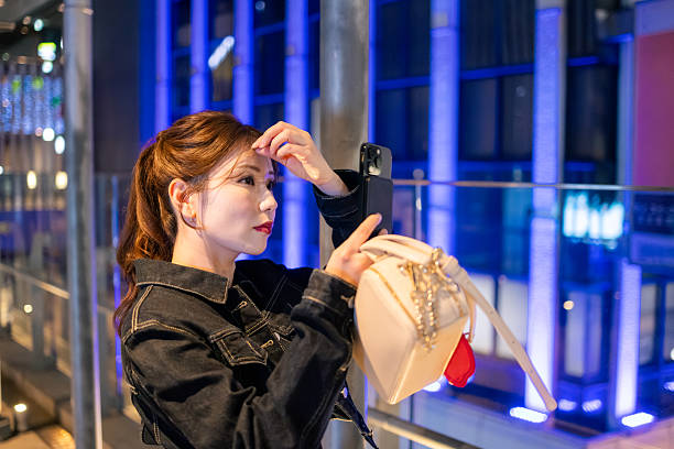 Woman in denim jacket checking bangs in night city