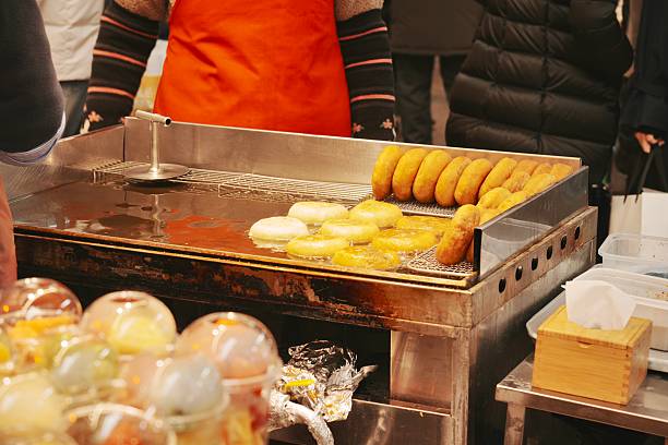 closeup of vendor cooking donuts on hot grill