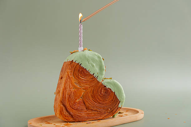 Burning festive candle holiday celebration Birthday anniversary Delightful and vibrant heartshaped pastry croissant treat, beautifully topped with colorful frosting nut galore. Mock up template copy space. Food experimentation viral dessert creative