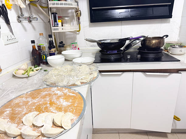 Hands rolling out dough with a wooden rolling pin on a floured board, preparing dumpling wrappers from scratch in a home kitchen for a festive meal in Xi'an, China.