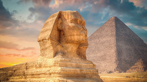 Close-up profile of the Great Sphinx with the Giza pyramid under a colorful sunset sky in Cairo, Egypt. Cinematic ancient landmark shot