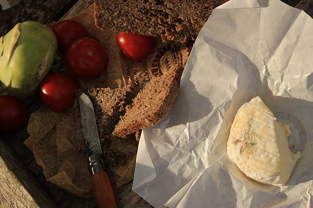 Rustic bread, fresh tomatoes, and creamy cheese served on a wooden table outdoors