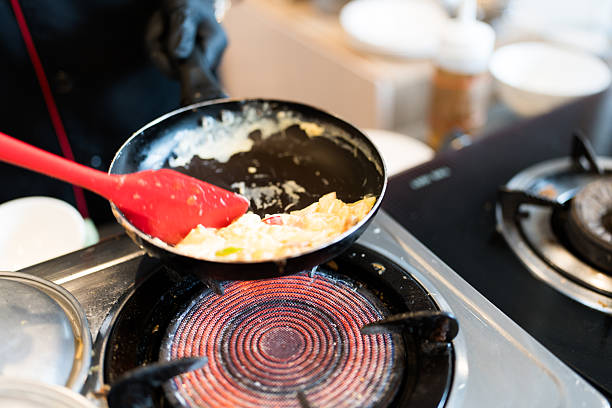 Buffet line kitchen and hotel chef cooking an omelette for a breakfast