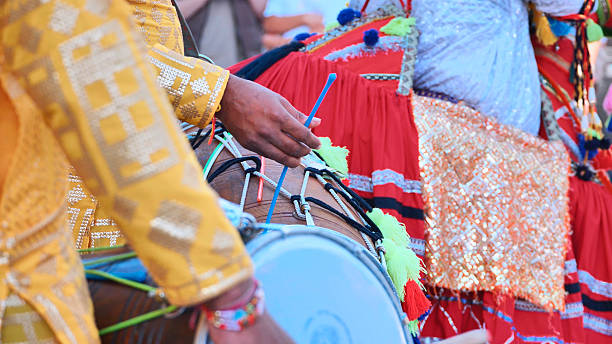 Indian drummer playing traditional dhol during cultural celebration, wearing vivid ethnic costume