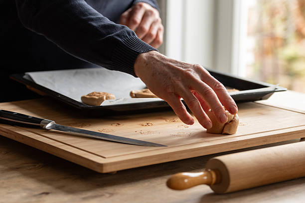 Close-up of man picking up cinnamon bun dough roll from wooden board