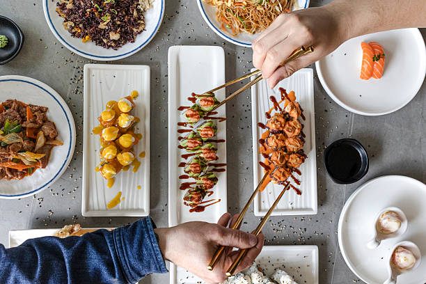 People sharing sushi and other asian dishes at restaurant