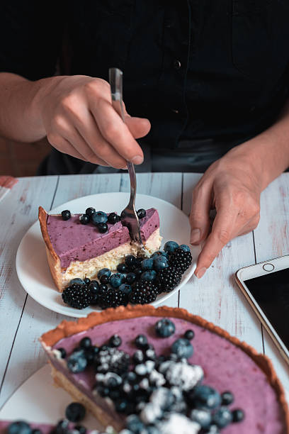 Cutting berry cheesecake slice with fork close up