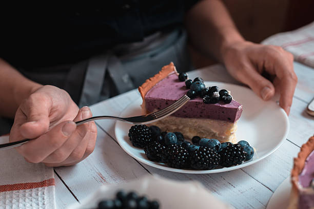 Eating berry cheesecake slice with fork close up