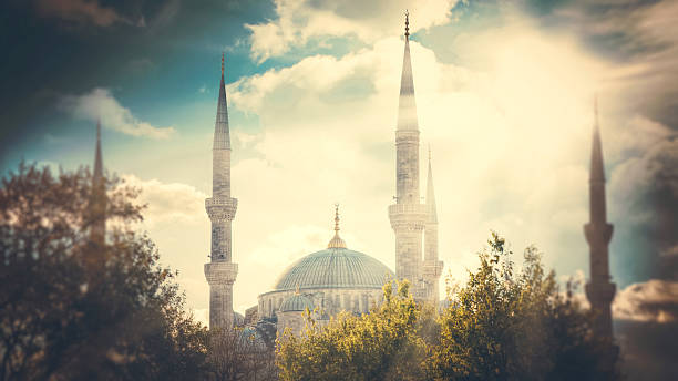 Artistic low angle view of Sultan Ahmed Mosque in Istanbul, Turkey. Divine light rays shining through clouds, dreamy vintage style with blurred trees