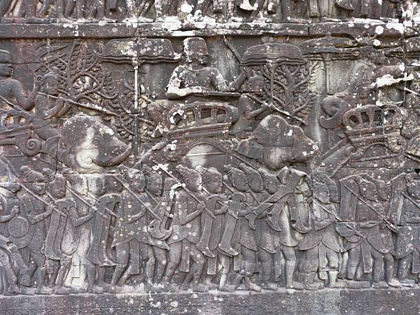 Ancient Khmer stone bas-relief depicting a ceremonial procession with figures and elephant imagery carved into the historic walls of Bayon temple, Angkor Thom, Siem Reap.